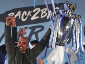 Manchester City coach Pep Guardiola holds the trophy as he celebrates with supporters at the Etihad Stadium in Manchester, England, Sunday May 12, 2019 the day they won the English Premier League title. Manchester City retained the Premier League trophy after coming from behind to beat Brighton 4-1 and see off Liverpool's relentless challenge on the final day of the season on Sunday.