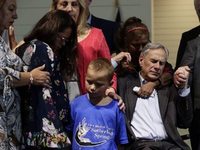 Texas Gov. Greg Abbott, right, holds hands with survivors during a dedication ceremony for a new sanctuary and memorial room at the First Baptist Church in Sutherland Springs, Texas, Sunday, May 19, 2019. In 2017 a gunman opened fire at the church and killed more than two dozen congregants.