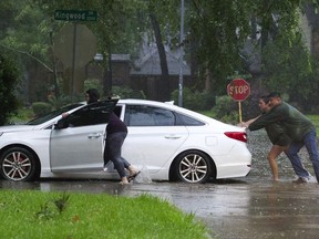 Residents push a stalled car as thunderstorms hit the Kingwood area flooding parts of Kingwood Drive, Tuesday, May 7, 2019, in Kingwood, Texas. Heavy rain is battering parts of southeast Texas prompting flash flood warnings, power outages and calls for water rescues.