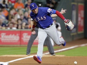 Texas Rangers third baseman Asdrubal Cabrera (14) loses the ball on the infield grounder by Houston Astros George Springer during the first inning of a baseball game Thursday, May 9, 2019, in Houston.