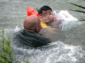 In this Friday, May 10, 2019 photo, Border Patrol Agent Brady Waikel rescues a 7-year-old boy from Honduras after he fell out of a makeshift raft and lost hold of his mother as Border Patrol agents respond to rafts crossing the Rio Grande River near Eagle Pass, Texas.