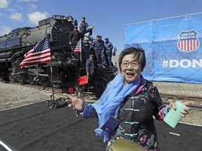 Margaret Yee, whose ancestors helped build the railroad, pose in front of the the Big Boy, No. 4014 during the commemoration of the 150th anniversary of the Transcontinental Railroad completion at Union Station Thursday, May 9, 2019, in Ogden, Utah. Yee, helped tap a ceremonial spike alongside Utah Gov. Gary Herbert and a descendant of Union Pacific's chief engineer on the project at the event Thursday in Ogden, Utah.