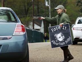 FILE - In this March 20, 2018, file photo, anti-abortion sidewalk counselor Laura Duran, offers reading material to a driver entering the Jackson Women's Health Organization's clinic, the only facility in the state that performs abortions, in Jackson, Miss. As abortion opponents cheer the passage of fetal heartbeat laws such as the one in Mississippi and other restrictions on the procedure, abortion-rights groups have been waging a quieter battle in courthouses around the country to overturn limits on providers.