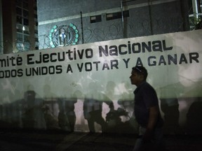 Opposition militants and journalists gather outside the Democratic Action political party headquarters, where a sign reads in Spanish "National Executive Committee. All united to vote and win," in Caracas, Venezuela, Wednesday, May 8, 2019.