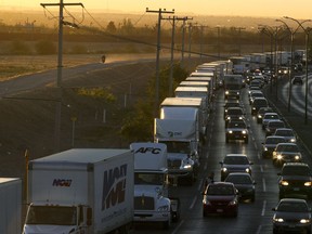 FILE- In this April 9, 2019, file photo, trucks wait to cross the border with the U.S. in Ciudad Juarez, Mexico.  In a surprise announcement that could compromise a major trade deal, President Donald Trump announced Thursday that he is slapping a 5% tariff on all Mexican imports to pressure the country to do more to crack down on the surge of Central American migrants trying to cross the U.S. border.