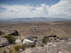 FILE - In this July 14, 2018, file photo, a sign warns of a falling danger on the crest of Yucca Mountain during a congressional tour Saturday, July 14, 2018, near Mercury, Nev. Nevada's long crusade to block the creation of a national nuclear-waste dump at Yucca Mountain has pitted it against a bipartisan group of lawmakers across the country, but a band of presidential hopefuls are joining the early voting state's cause.
