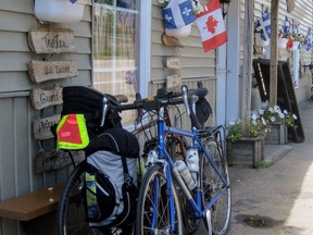 In this Aug. 7, 2015, photo, Quebec and Canadian flags greet visitors at a shop on Isle-aux-Coudres, where a road circling the island shore provides a perfect loop for lovers of quiet roads, gentle hills, flats along the water and eye-candy vistas of mountains you don't have to climb. A free, 15-minute car ferry gets you to the island from Quebec's Charlevoix mainland.