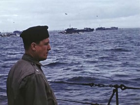 Hollywood director George Stevens stands on a ship off the coast of France on D-Day, June 6, 1944. Seventy-five years later, surprising color images of the D-Day invasion and aftermath bring an immediacy to wartime memories. They were filmed by Hollywood director George Stevens and rediscovered years after his death.