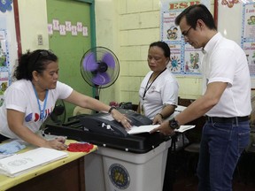 Manila mayor candidate Francisco "Isko" Moreno Domagoso, right, is helped by election workers as he casts his vote at the Manuel L. Quezon elementary school in Manila, Philippines, Monday, May 13, 2019. Filipinos began voting in midterm elections highlighted by a showdown between President Rodrigo Duterte's allies who aim to dominate the Senate and an opposition fighting for check and balance under a leader they regard as a looming dictator.