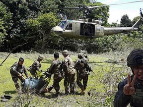 In this photo released by the Joint Task Force Sulu, Philippine soldiers carry bodies towards a military helicopter as pursuit operations continue in Patikul, Sulu province, southern Philippines, Friday, May 31, 2019. A long-held Dutch hostage was shot and killed by his Abu Sayyaf captors Friday when he tried to escape during a gunbattle in the southern Philippines, military officials said. (Joint Task Force Sulu via AP)