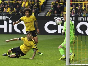 Dortmund's Christian Pulisic, on the ground, scores the opening goal past Duesseldorf goalkeeper Michael Rensing, right, during the German Bundesliga soccer match between Borussia Dortmund and Fortuna Duesseldorf in Dortmund, Germany, Saturday, May 11, 2019.