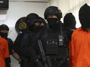 Indonesian Special Detachment 88 anti-terror police unit escorts terror suspect during a press conference at in Jakarta, Indonesia, Friday, May 17, 2019. Police say they have arrested suspected militants following a tipoff about a possible attack during the announcement of presidential election results next week.
