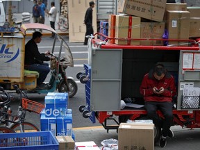 A private delivery company's courier sits on his delivery cart sorting boxes of goods for his customers outside an office building at the Central Business District in Beijing, Wednesday, May 8, 2019. Washington and Beijing have raised tariffs on billions of dollars of each other's exports, disrupting trade in goods from soybeans to medical equipment. Estimates of lost potential sales so far range as high as $25 billion.