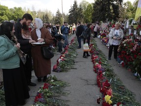 People lay flowers as they gather outside the burnt trade union building to commemorate the five-year anniversary of deadly clashes which killed dozens of demonstrators supporting Ukraine's government and pro-Russia protesters, in Odessa, Ukraine, Thursday, May 2, 2019. Five years after 48 people died in clashes in the Ukrainian city of Odessa, including dozens in a burning building, the UN human rights monitoring mission in the country is criticizing authorities for delays in prosecution and investigation of the violence.