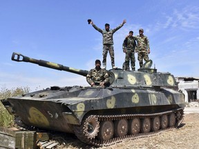In this photo released by the Syrian official news agency SANA, Syrian army soldiers flash the victory sign as they stand on their tank in the village of Kfar Nabuda, in the countryside of the Hama province on Saturday, May 11, 2019. The Britain-based Syrian Observatory for Human Rights said government forces are now in control of nine villages forming an L shape at the far southern corner of the rebel stronghold. The villages include the strategic village of Kfar Nabuda and the elevated Qalaat Madiq, giving the government troops an advantage over the insurgents. (SANA via AP)