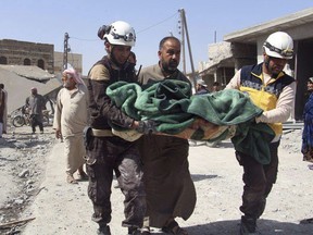 This photo provided by the Syrian Civil Defense group known as the White Helmets, shows members of the Syrian Civil Defense workers carrying a victim after a deadly airstrike hit a market killing several people in the village of Ras el-Ain, in the northwestern province of Idlib, Syria, Tuesday, May 7, 2019. Opposition activists say government forces have intensified their bombardment of rebel-held towns and villages in northwestern Syria. (Syrian Civil Defense White Helmets via AP)