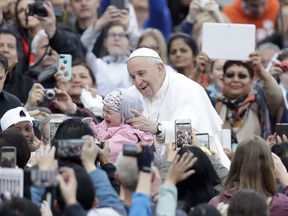 Pope Francis is given a child to bless as he is driven through the crowd during his weekly general audience in St. Peter's Square, at the Vatican, Wednesday May 15, 2019.