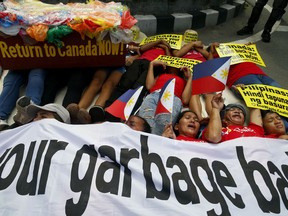 Environmentalists stage a mock die-in protest outside the Canadian Embassy to demand the Canadian government to speed up the removal of several containers of garbage that were shipped to the country Tuesday, May 21, 2019, in Manila, Philippines. The Philippines recalled its ambassador and consuls in Canada last week over Ottawa's failure to comply with a deadline to take back 69 containers of garbage that Filipino officials say were illegally shipped to the Philippines years ago.