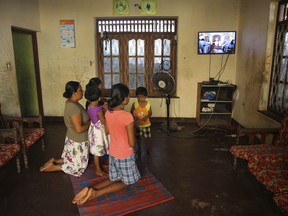 FILE - In this Sunday, April 28, 2019 file photo, a Sri Lankan catholic family prays inside their home watching a live television transmission of Archbishop of Colombo Cardinal Malcolm Ranjith, in Negombo, Sri Lanka. Sri Lankan Catholic officials said Thursday, May 9, church-run schools that have been closed since Easter Sunday bomb attacks are expected to reopen next week, and Sunday Masses will resume this weekend if security conditions are appropriate.