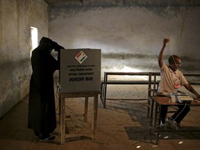 FILE - In this Thursday, April 11, 2019 file photo, an Indian Muslim woman casts her vote at a polling station in village Sawaal near Meerut, Uttar Pradesh, India.  The final phase of India's marathon general election will be held on Sunday, May 19. The first of the election's seven staggered phases was held on April 11. Vote counting is scheduled to start on May 23. India has 900 million eligible voters.