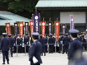 Visitors are escorted by police officers to see Japan's new Emperor Naruhito prior to his first public appearance with his imperial families at Imperial Palace Saturday, May 4, 2019, in Tokyo.