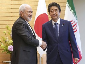 Iranian Foreign Minister Mohammad Javad Zarif, left, and Japanese Prime Minister Shinzo Abe, right, shake hands at Abe's official residence in Tokyo Thursday, May 16, 2019.