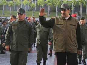 In this photo released by Miraflores Press Office, Venezuela's President Nicolas Maduro, right, accompanied by his Defense Minister Vladimir Padrino Lopez, waves upon his arrival to Fort Tiuna for a meeting with troops, in Caracas, Venezuela, Thursday, May 2, 2019.