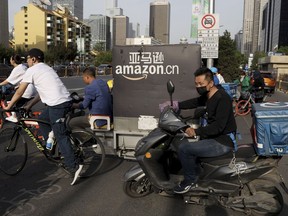 In this Wednesday, May 8, 2019, photo, a delivery man bearing U.S. commerce giant Amazon's brand is seen in downtown Beijing. China said Thursday it will retaliate if President Donald Trump goes ahead with more tariff hikes in a fight over technology and trade, ratcheting up tensions ahead of negotiations in Washington.