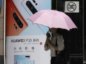 A woman walks past advertisement for Huawei smartphones in Beijing on Thursday, May 16, 2019. In a fateful swipe at telecommunications giant Huawei, the Trump administration issued an executive order Wednesday apparently aimed at banning its equipment from U.S. networks and said it was subjecting the Chinese company to strict export controls.