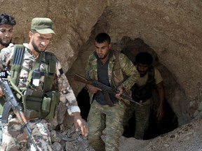 FILE - In this Sept. 9, 2018 file photo, fighters with the Free Syrian army exit a cave where they live, in the outskirts of the northern town of Jisr al-Shughur, Syria, west of the city of Idlib. After eight months of relative calm, Idlib is once again a theater for bloody military operations as Syrian government troops, backed by Russia, push their way into the rebel-held enclave in a widening offensive. The violence in May 2019 threatens to completely unravel a crumbling cease-fire agreement reached between Turkey and Russia last September.