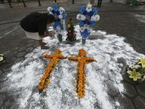 FILE - In this Oct. 21, 2015 file photo a woman creates a makeshift memorial, in front of the Municipal Palace in Ajalpan, Puebla, Mexico, for two pollsters mistaken for criminals who were killed and burned by a mob. Mexico's National Human Rights Commission released report Wednesday, May 22, 2019, said vigilante attacks in which mobs injure or kill people suspected of wrongdoing are increasing.