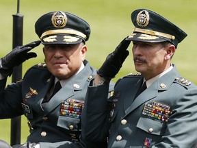 FILE - In this Dec. 17, 2018 file photo, Army Commander Gen. Nicacio Martinez Espinel, right, salutes during a swearing-in ceremony for the new military and police commanders, in Bogota, Colombia. New evidence has emerged linking Martinez Espinel to the alleged cover up of civilian killings more than a decade ago. The documents, provided to The Associated Press by a person familiar with an ongoing investigation into the extrajudicial killings, come as Martinez Espinel faces mounting pressure to resign over orders he gave troops this year, 2019, to step up attacks in what some fear could pave the way for a return of serious human rights violations.