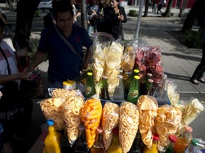 FILE - In this July 5, 2016 file photo, a street vendor sells fried snacks packaged in plastic bags in Mexico City. Mexico City lawmakers announced on Thursday, May 9, 2019 they have passed a ban on plastic bags, utensils and other disposable plastic items to take effect at the end of 2020, giving businesses more than a year to make the switch to biodegradable products.