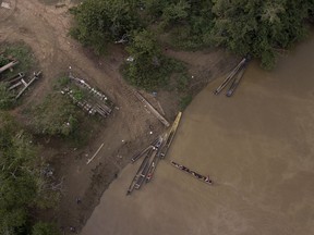 In this May 10, 2019 photo, a group of migrants are boated across the Chucunaque river as they arrive in Peñitas, Darien Province, Panama. Darien's rivers can rise suddenly and furiously, and in recent weeks at least 10 migrants were reportedly swept to their deaths.