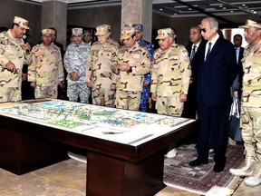FILE - In this Feb. 25, 2018 file photo, provided by Egypt's state news agency MENA, Egyptian President Abdel-Fattah el-Sissi, center, attends the inauguration of the East Suez Canal Counter-Terrorism command, in Sinai, Egypt. In a 134-page report released Tuesday, May 28, 2019, Human Rights Watch, a leading international rights group, accused Egypt's security forces of committing widespread abuses against civilians -- some of which "amount to war crimes" -- in the Sinai Peninsula, where Egypt has been battling Islamic militants for years. The group said it documented "crimes, including mass arbitrary arrests, enforced disappearances, torture, extrajudicial killings, and possibly unlawful air and ground attacks against civilians."