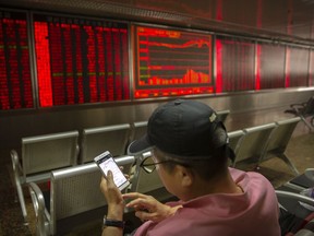 A Chinese investor uses his smartphone as he monitors stock prices at a brokerage house in Beijing, Friday, May 10, 2019. Asian shares were mostly higher Friday but benchmarks in Shanghai and Hong Kong gave up earlier strong gains amid uncertainty over the potential outcome of trade talks between China and the U.S.
