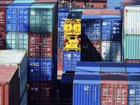In this Thursday, May 23, 2019, photo, a crane lifts a shipping container at a port in Qingdao in eastern China's Shandong province. Stepping up a propaganda offensive against Washington, China's state media on Friday accused the U.S. of seeking to "colonize global business" by targeting telecom equipment giant Huawei and other Chinese companies. (Chinatopix via AP)