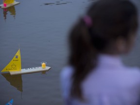 Handmade boats with the names of Nazi concentration camps float in a lake during ceremony marking the annual Holocaust Remembrance Day in Tel Aviv, Israel, Wednesday, May 1, 2019. Israel marking the annual Day of Remembrance for the six million Jewish victims of the Nazi genocide who perished during World War II. Hebrew reads "to remember".