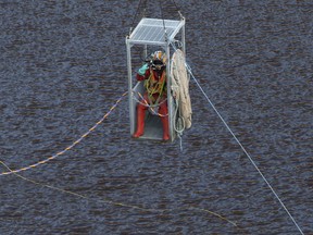 A diver is lowered into a man-made lake to search for suitcases containing the bodies of three murdered victims, near the village of Mitsero outside of the capital Nicosia, Cyprus, Thursday, May 2, 2019. The justice minister in Cyprus resigned amid mounting criticism that police bungled their investigations when some of the seven foreign women and girls slain by a serial killer were initially reported missing.