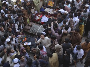 Afghan people stand over bodies of civilians during a protest in Nangarhar province east of Kabul, Afghanistan, Saturday, May 25, 2019. Afghan officials say at least six civilians, including a woman and two children, have been mistakenly killed in an Afghan security forces raid against Taliban fighters in eastern Nangarhar province.