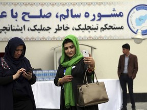 A delegate poses for a selfie photo backdropped by a sign written in Persian "Good consultation, peace with dignity", while attending the first day of the Afghan Loya Jirga meeting in Kabul, Afghanistan, Monday, April 29, 2019.  Afghanistan's president Ashraf Ghani opened the Loya Jirga grand council on Monday with more than 3,200 prominent Afghans attending to seek an agreed common approach for future peace talks with the Taliban, but the gathering may further aggravate divisions within the U.S.-backed government.