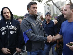 Opposition leader Leopoldo Lopez, center, is greeted by a supporter outside La Carlota air base in Caracas, Venezuela, Tuesday, April 30, 2019. Lopez, who had been under house arrest for leading an anti-government push in 2014, said he had been freed by soldiers and called for a military uprising.