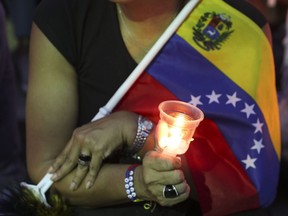 An opponent to Venezuela's President Nicolas Maduro holds a candle during a vigil for those killed in street fighting over the past week in Caracas, Venezuela, Sunday, May 5, 2019. Opposition leader Juan Guaid called in vain for a military uprising to overthrow President Nicolas Maduro, and five people were killed in clashes between protesters and police.
