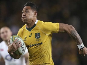 FILE - In this June 25, 2016, file photo, Australian rugby union player Israel Folau, wearing tape on his wrist adorned with a cross, runs toward the try line to score against England during their rugby union test match in Sydney. The 30-year-old Folau will appear before a code of conduct hearing at Rugby Australia's headquarters in Sydney to determine the playing future of the star Wallabies fullback on Saturday, May 4, 2019.