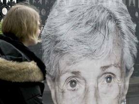 A women looks at destroyed and repaired pictures by the artist Luigi Toscano showing Holocaust survivors in Vienna, Austria, Tuesday, May 28, 2019.  The creator of a photo exhibit of Holocaust survivors in Austria expressed dismay Tuesday that his portraits were slashed and daubed with swastikas in three attacks this month.