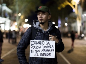 A man displays a sign hung around his neck that reads in Spanish "When the police shoots, its the state that aims" during a march against police brutality, in Buenos Aires, Argentina, Friday, May. 24, 2019. Argentines protested after officers on Monday fired shots that led to the deaths of three teenagers and a young man in a car chase.
