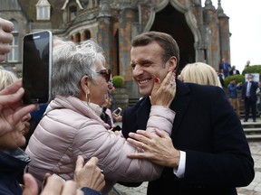 French President Emmanuel Macron smiles to a supporter after voting in the European parliamentary elections in Le Touquet, northern France, Sunday May 26, 2019. France is looking at an epic battle between pro-EU centrist President Emmanuel Macron and anti-immigration, far-right flagbearer Marine Le Pen in the European Parliament vote, a duel over Europe's basic values.