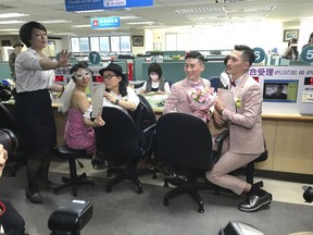 Two same-sex couples show their legal marriage certificates at the registration office in Xingyi District in Taipei, Taiwan, Friday, May 24, 2019. Hundreds of same-sex couples in Taiwan are rushing to the household registration office on the first day that a landmark decision to legalize same-sex marriage has taken effect.