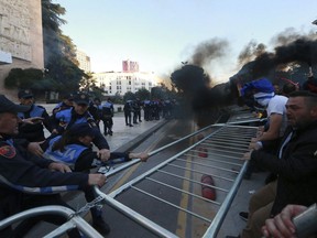 Protesters try to remove a metal fence during clashes with police outside the Government building in Tirana, Saturday, May 11, 2019. Thousands of supporters of the Albania's center-right opposition protested in Tirana Saturday, calling for the left-wing government to resign and for an early parliamentary election.