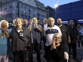 Supporters of New Democracy opposition conservative party react as they watch an exit poll at a campaign kiosk, in Athens, Sunday, May 26, 2019. New Democracy party is projected to win the European election, according to an exit poll jointly conducted by five Greek polling firms.